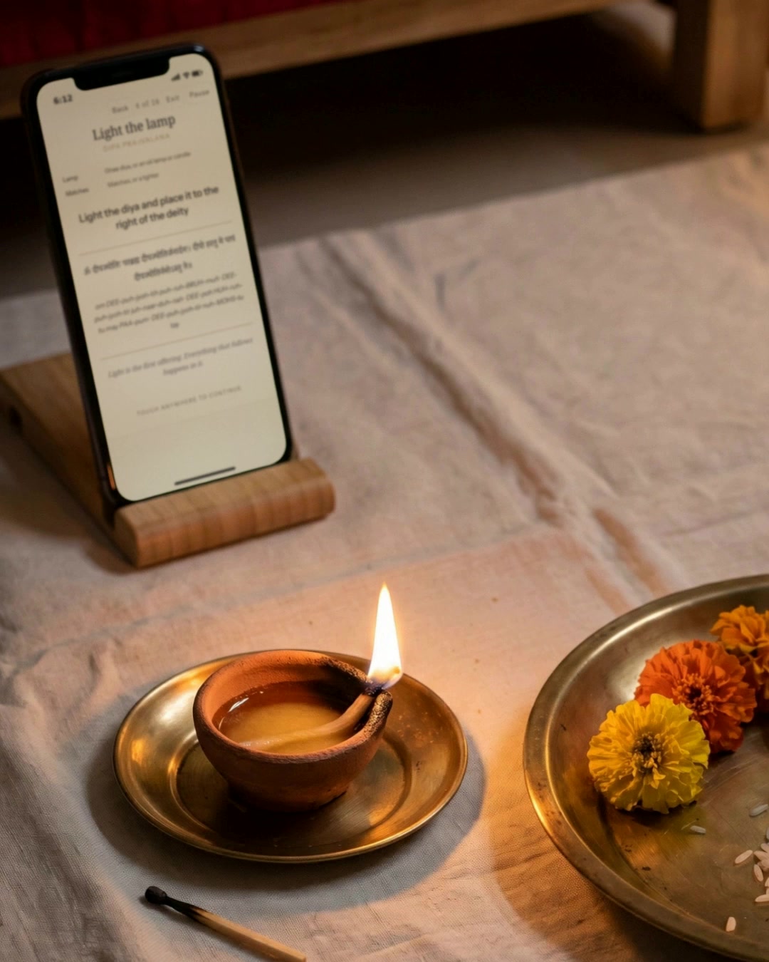 A lit diya beside a phone