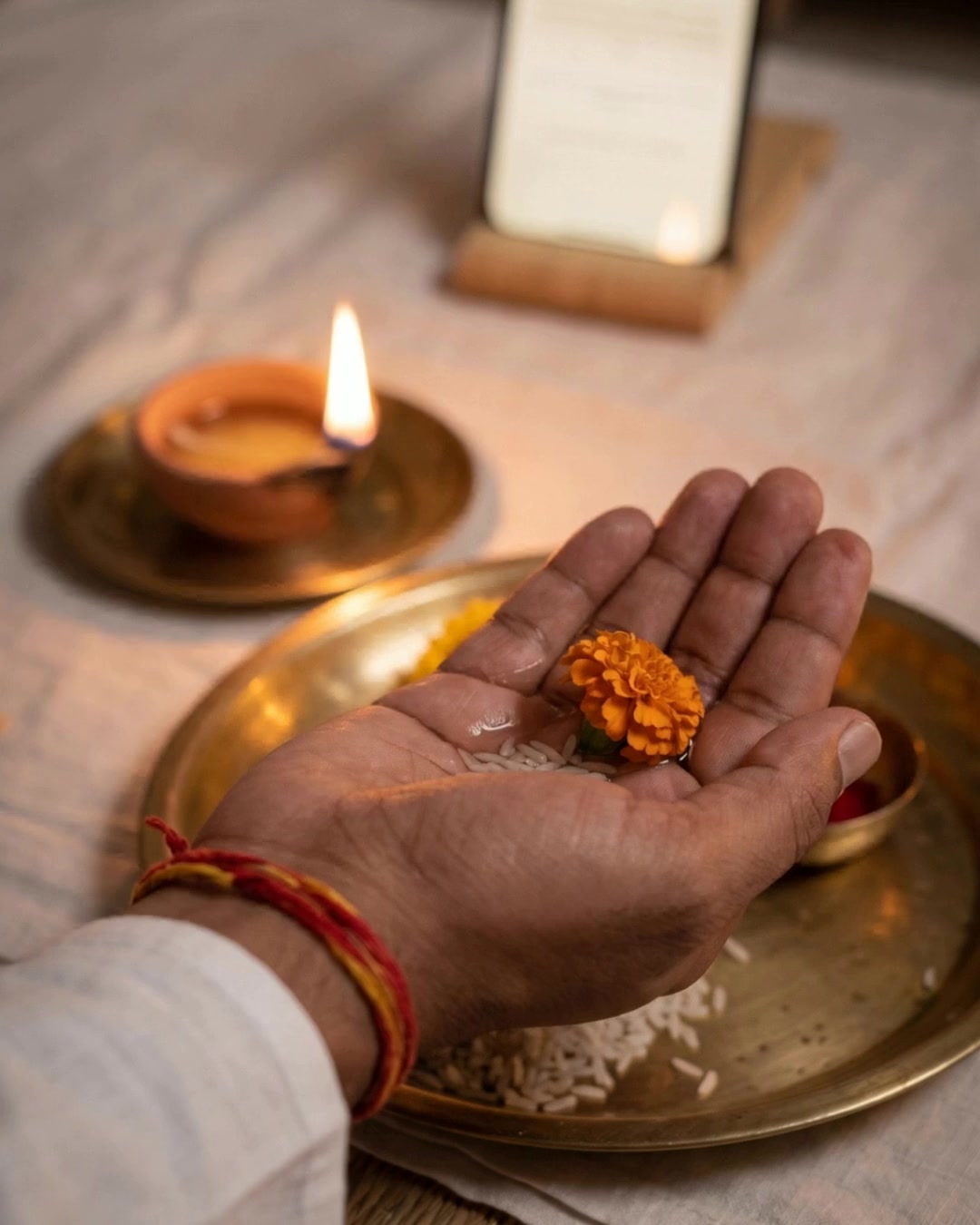 A cupped right hand holding water, rice and a marigold